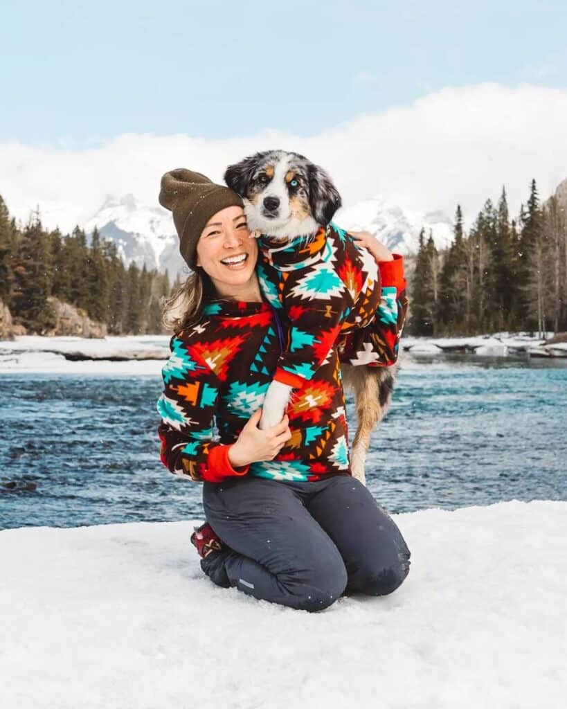 Victoria, kneeling down, hi-fiving Farley with the Canadian Rockies in the background