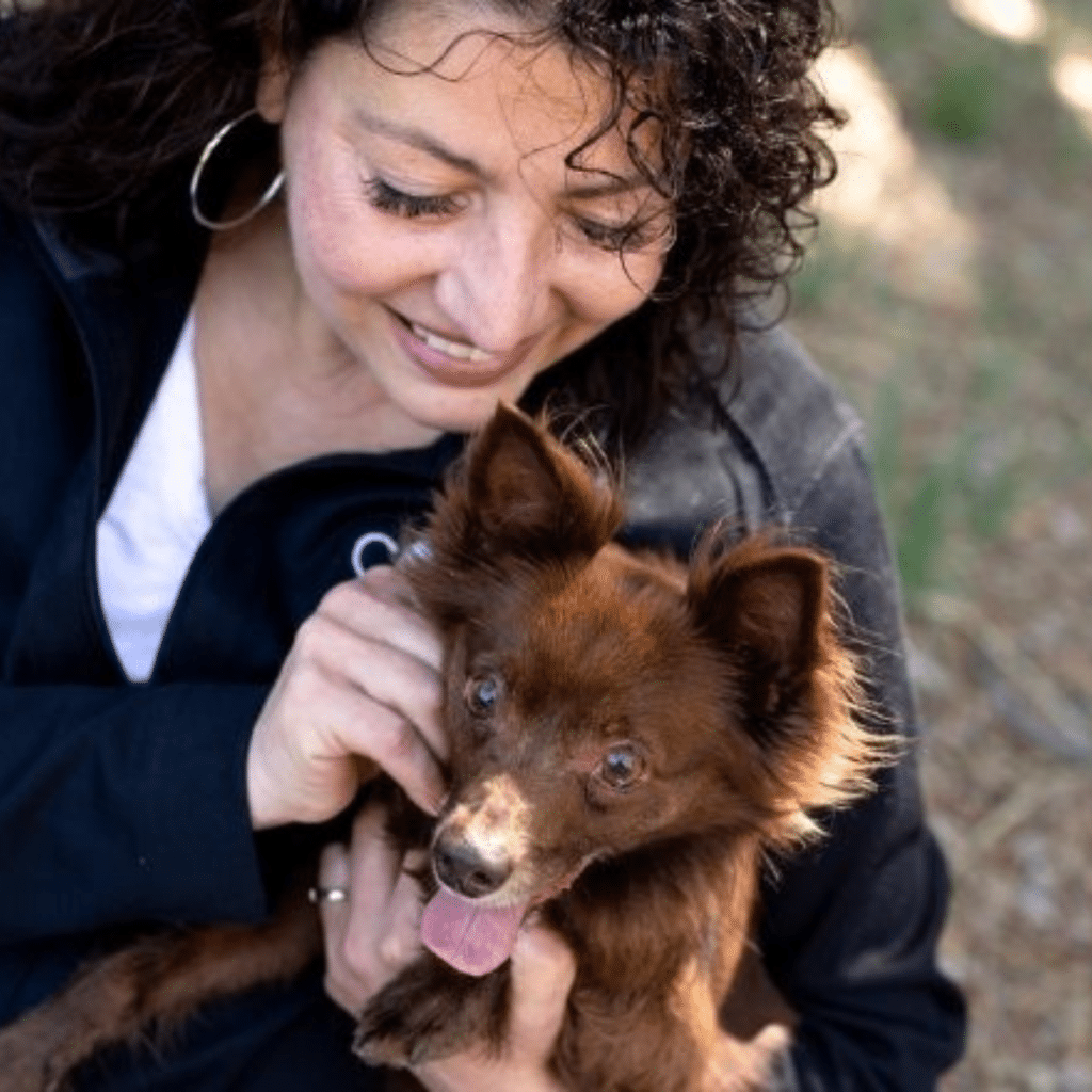 headshot of Malena DeMartini holding a small brown dog